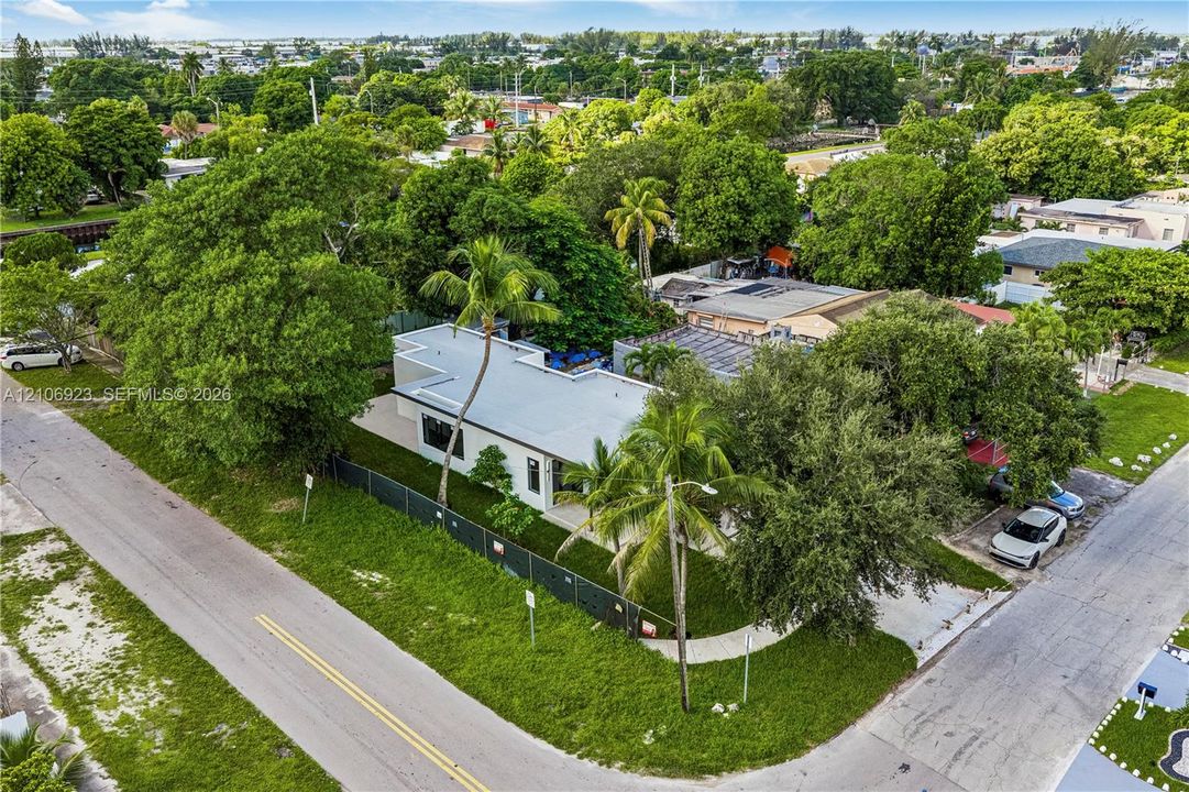 Single-story residence featuring a flat roofline, corner lot placement, mature landscaping, palm trees, and an asphalt driveway