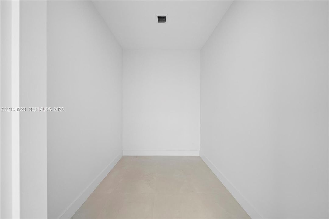 Minimalist interior space featuring neutral wall tones, large-format tile flooring, and recessed ceiling lighting