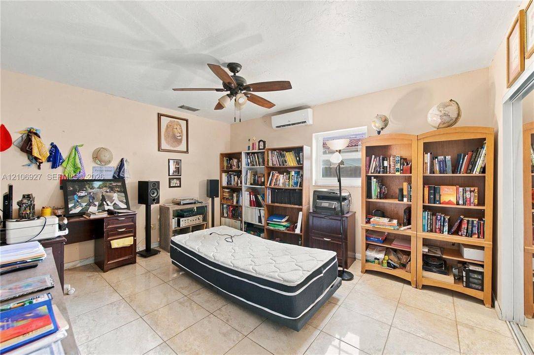 Room featuring neutral wall paint, polished tile flooring, ceiling fan with integrated lighting, and a wall-mounted ductless air conditioning unit