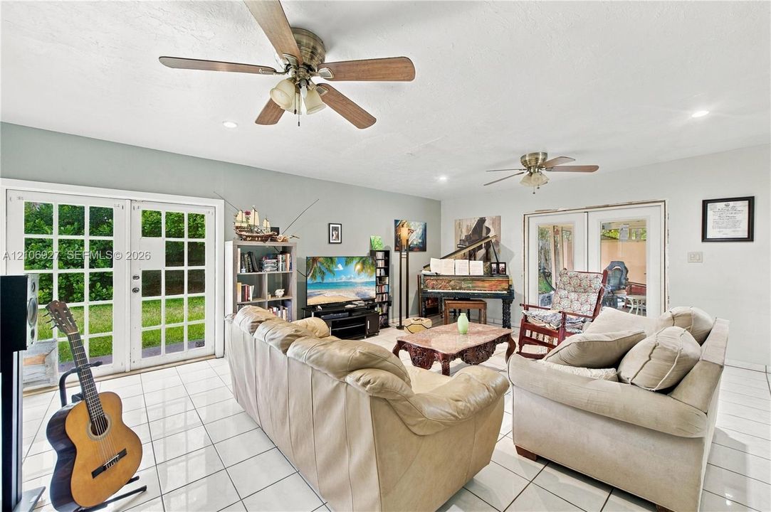 Spacious interior featuring white ceramic tile flooring, dual ceiling fans, and two sets of double-paned French doors