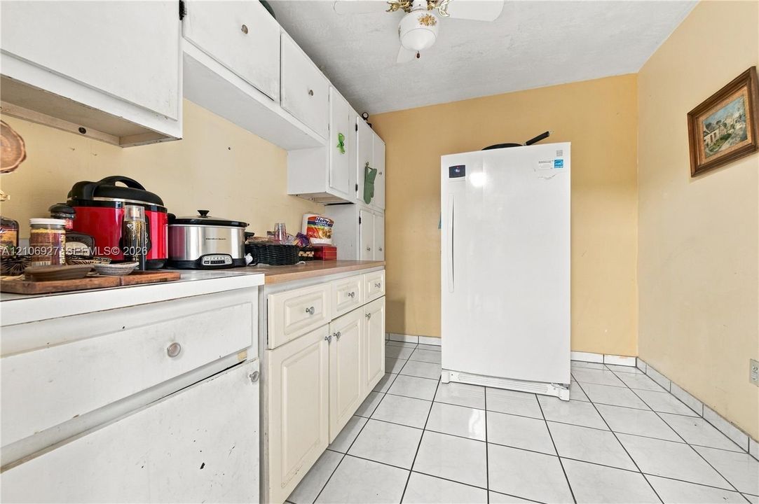Kitchen featuring white raised-panel cabinetry, ceramic tile flooring, and a ceiling-mounted light fixture