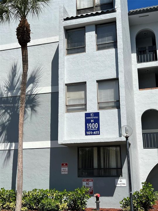 Multi-story stucco exterior featuring arched architectural detailing, sliding windows, and exterior pole lighting
