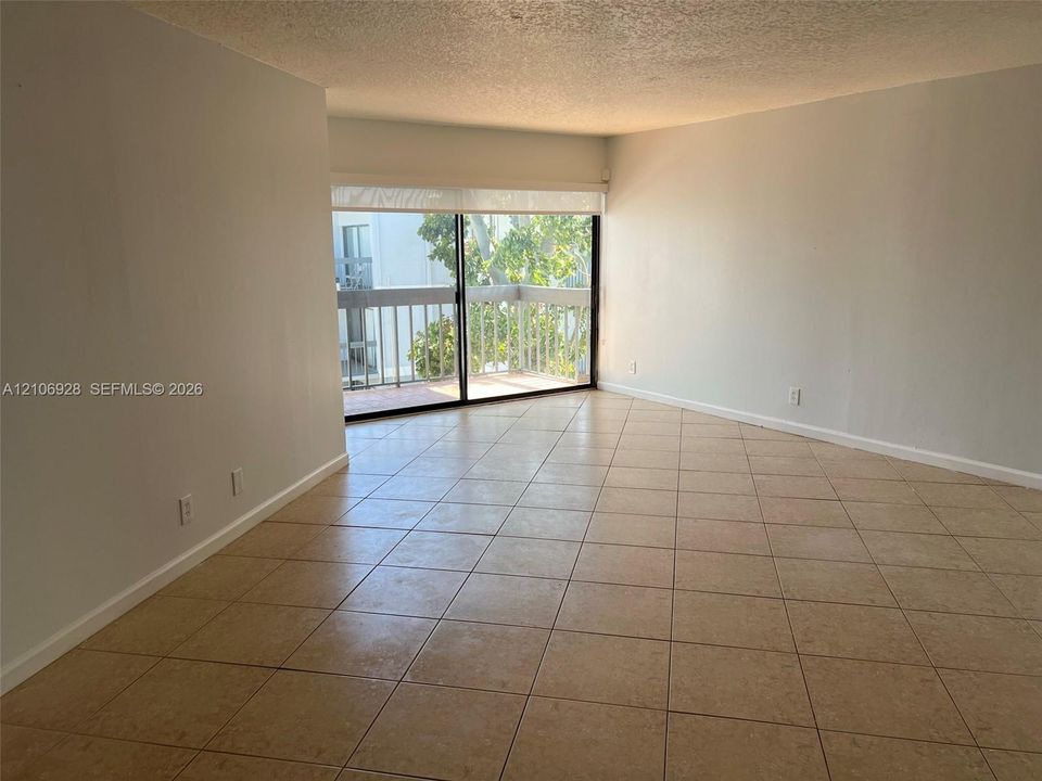 Interior space featuring neutral wall tones, large-format tile flooring, and a sliding glass door providing access to a private balcony