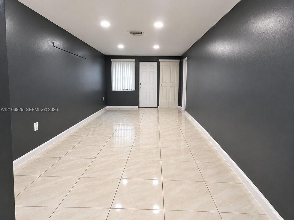 Interior space featuring large-format neutral tile flooring, recessed ceiling lighting, and dark-toned wall finishes