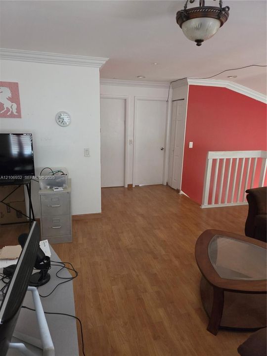 Wood-finish flooring, crown molding, semi-flush mount lighting, and white wooden stair railings