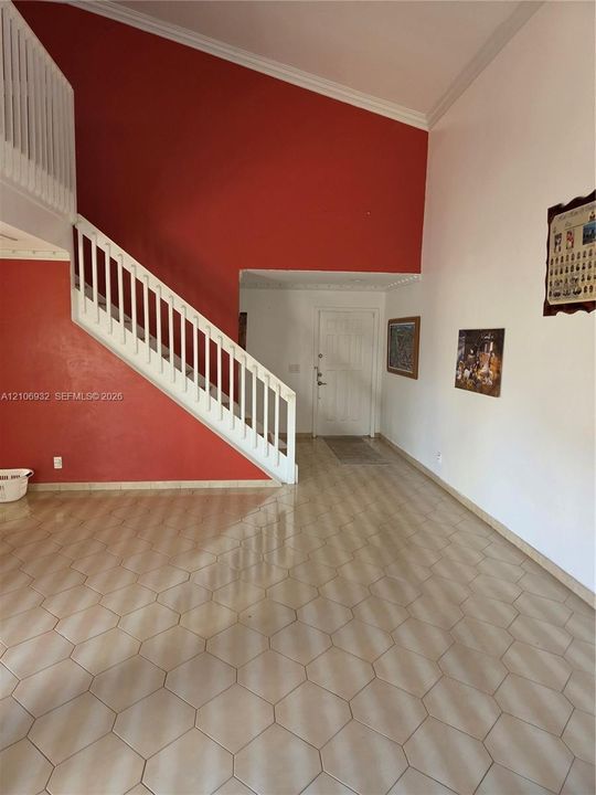 Foyer featuring high vaulted ceilings, hexagonal ceramic tile flooring, and a staircase with a white wooden railing