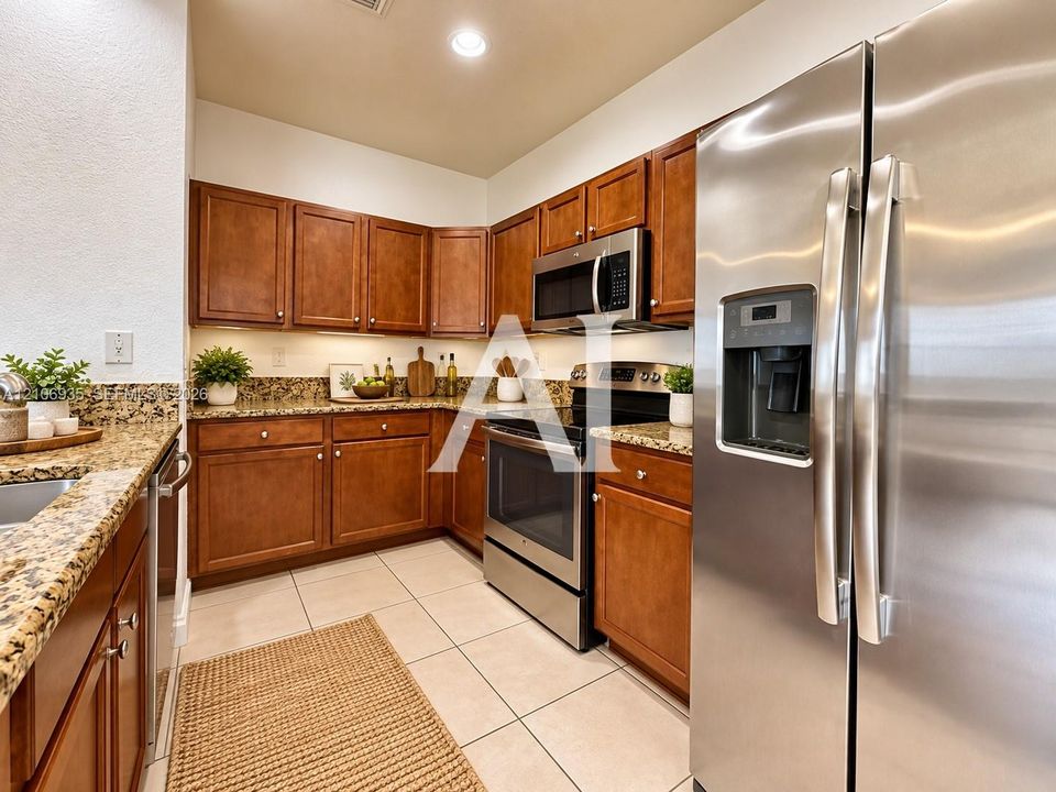 Kitchen featuring wood cabinetry, stone countertops, stainless steel appliances, and ceramic tile flooring