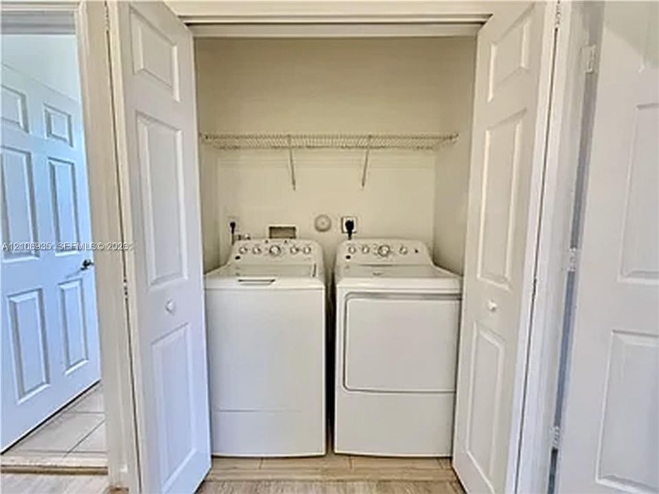 Laundry closet featuring a wire shelving rack, dual-panel folding doors, and neutral tile flooring