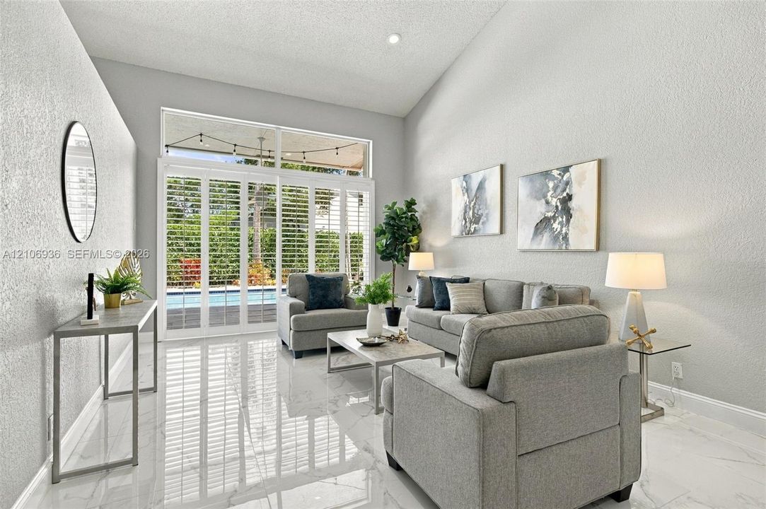 Vaulted ceilings, large-format tile flooring, and floor-to-ceiling glass sliding doors with plantation shutters