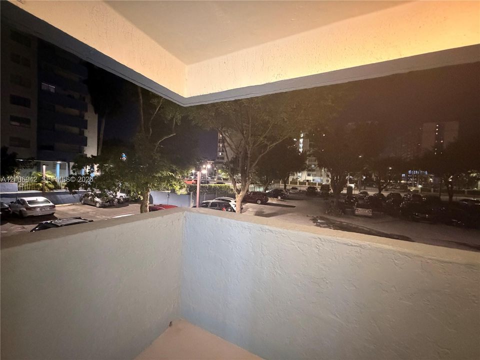 Covered balcony featuring textured concrete walls and solid surface flooring
