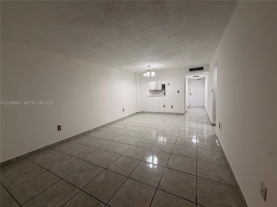 Open interior space featuring light-toned tile flooring, a pass-through window to an additional area, and a ceiling-mounted light fixture
