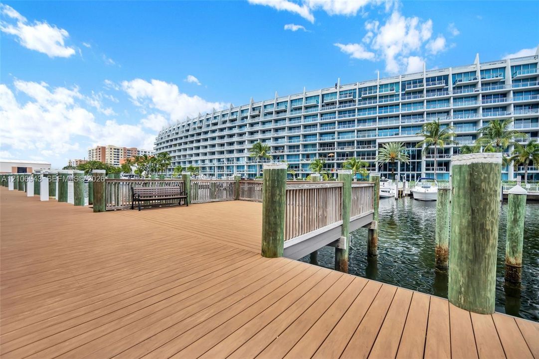 Waterfront wooden dock featuring composite decking, integrated wood-slatted railing, and structural pilings