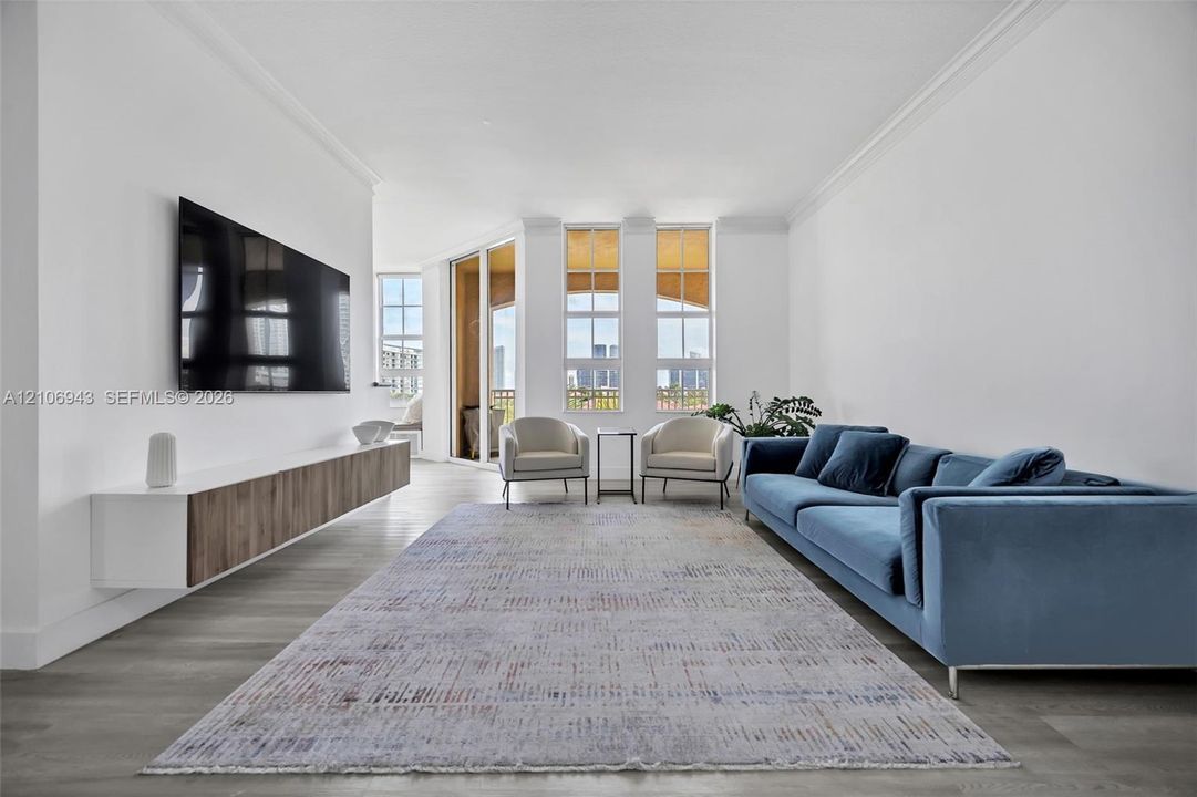 Living area featuring wood-finish flooring, crown molding, a wall-mounted floating cabinet with wood-finish cabinetry, and floor-to-ceiling windows