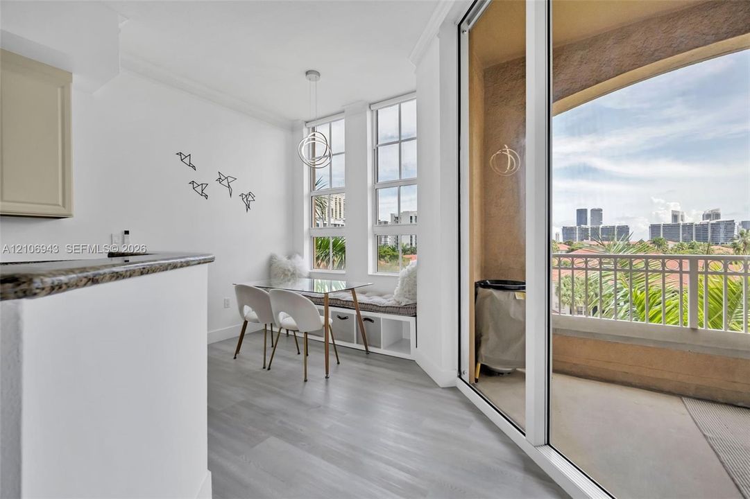 Dining area featuring wood-finish flooring, built-in window seating with integrated storage, large multi-pane windows, a contemporary circular pendant light, and sliding glass doors opening to a covered balcony