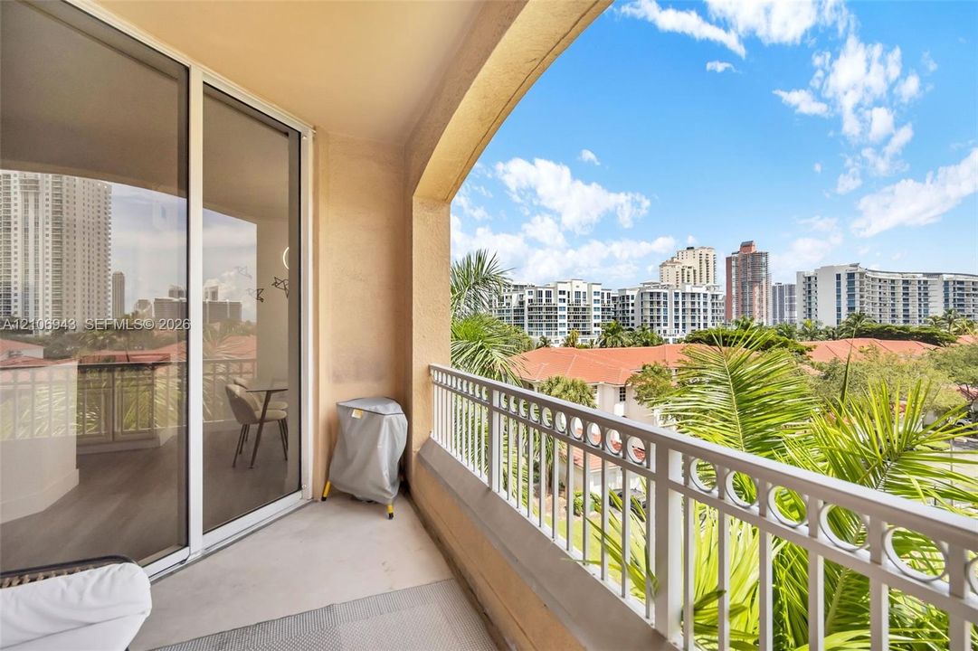 Covered balcony featuring a metal railing, concrete flooring, and sliding glass door access