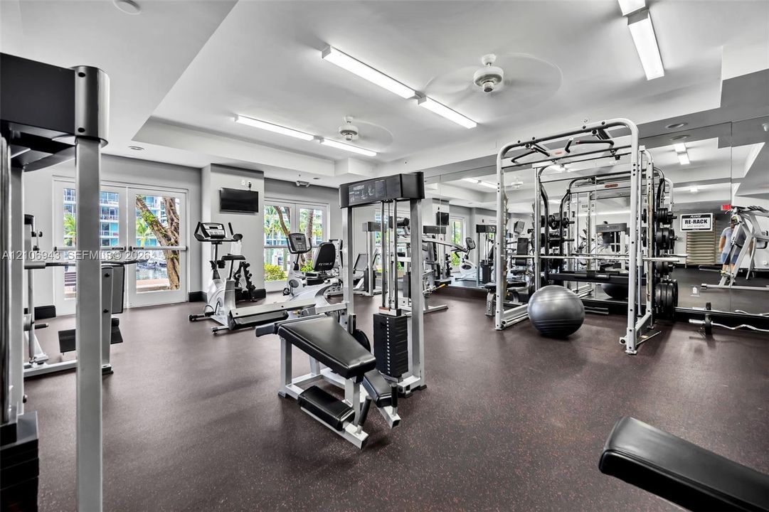Fitness center featuring rubber flooring, mirrored walls, recessed lighting, and dual ceiling fans