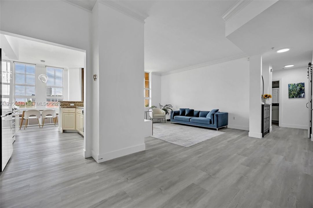 Open-concept interior featuring wood-finish flooring, crown molding, recessed lighting, and multi-pane windows