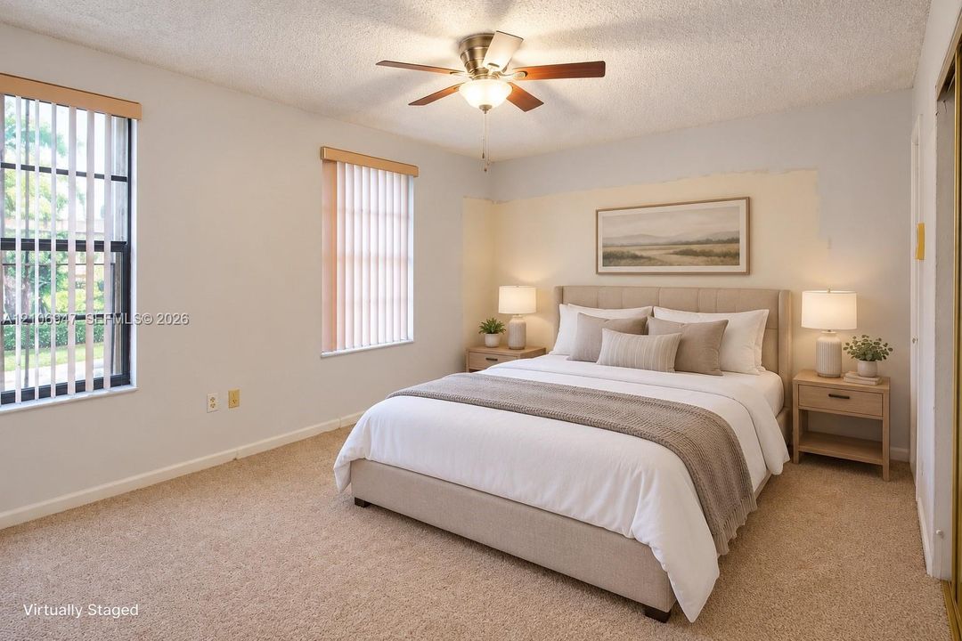 Bedroom featuring wall-to-wall carpeting, dual windows with vertical blinds, and a central ceiling fan with an integrated light fixture