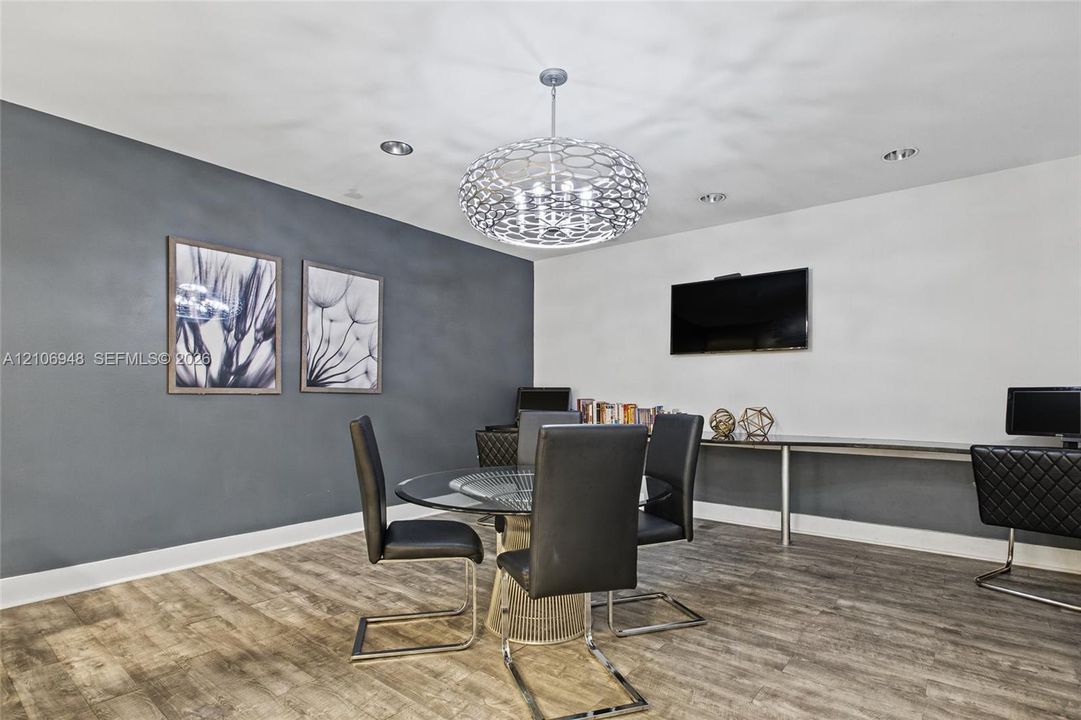 Wood-finish flooring, dark-toned accent wall, recessed lighting, and a modern tiered spherical chandelier