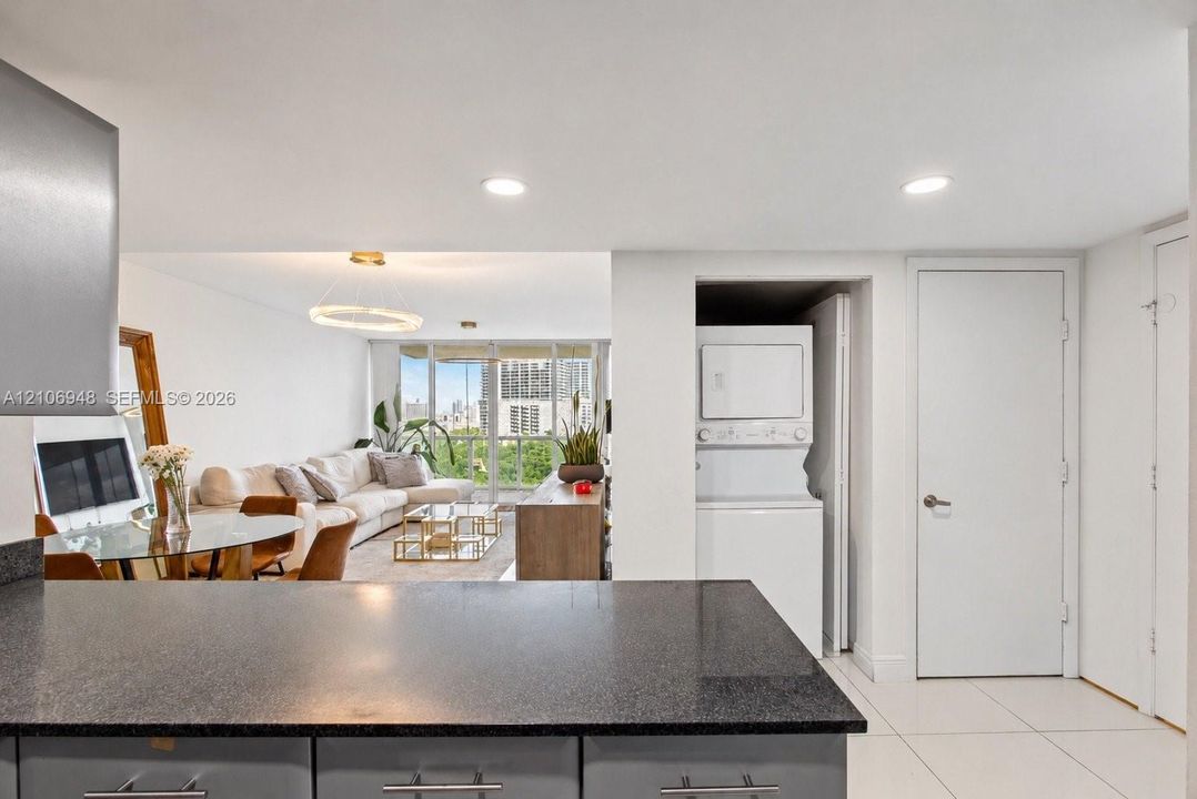 Granite-finish countertop, recessed lighting, and built-in stacked laundry appliances