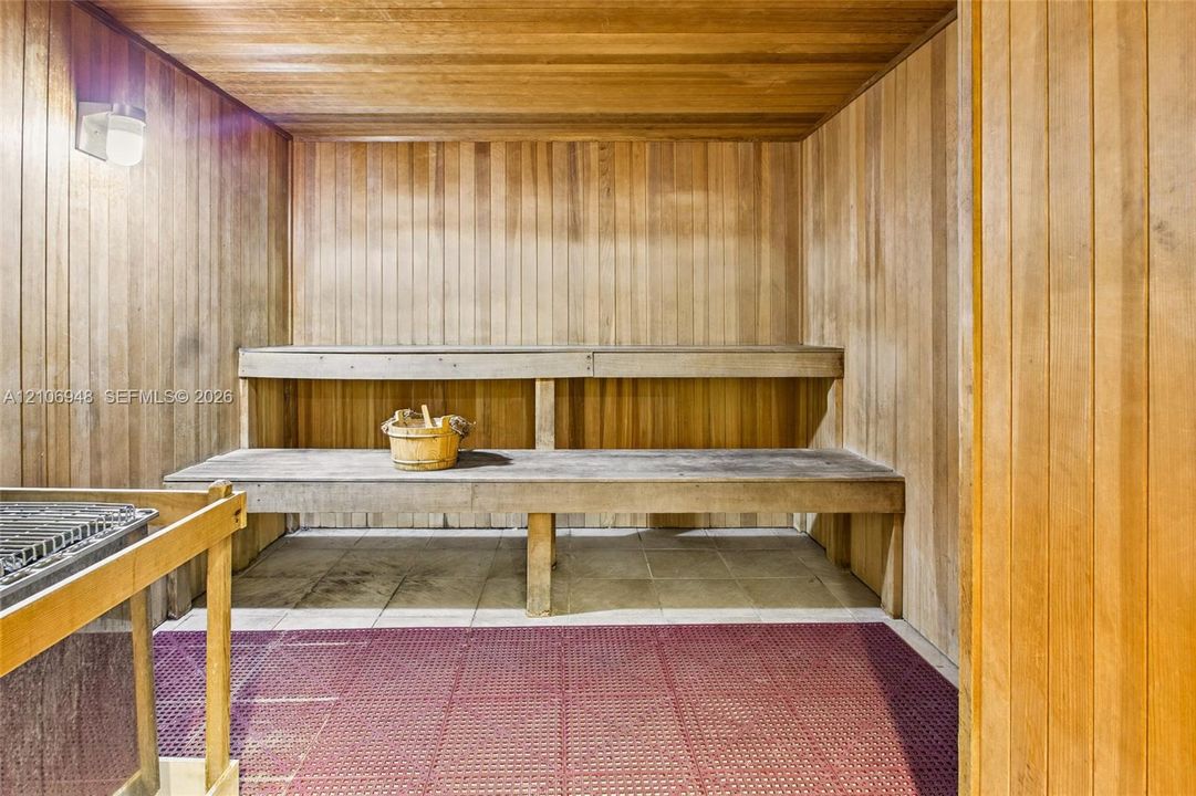 Sauna featuring wood-paneled walls and ceiling, tiered wood benches, tile flooring, and integrated wall lighting