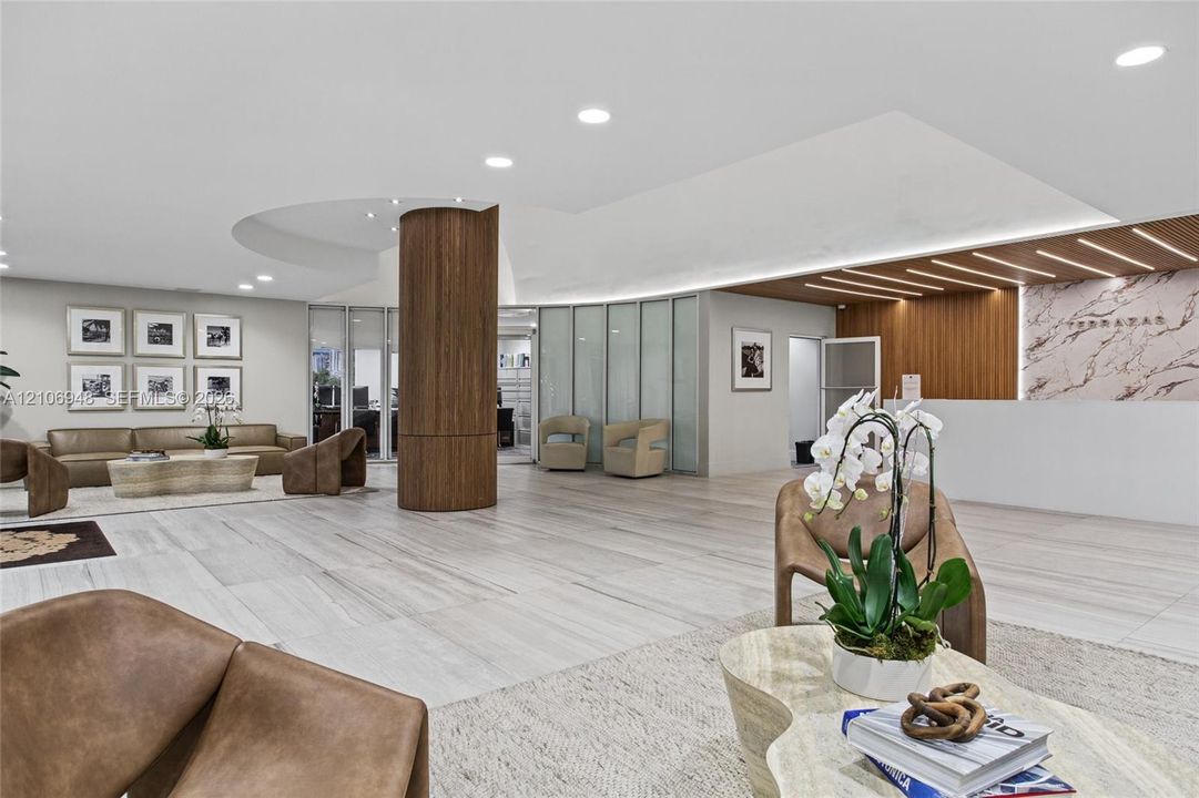 Reception area featuring large-format tile flooring, a cylindrical wood-finish architectural column, recessed lighting, stone-surfaced reception desk, and decorative wood slat ceiling accents