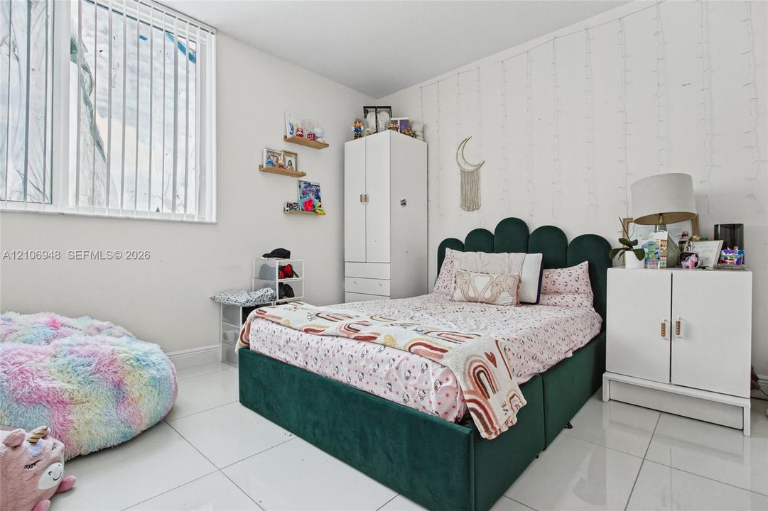 Room featuring large-format white tile flooring and floor-to-ceiling vertical blinds