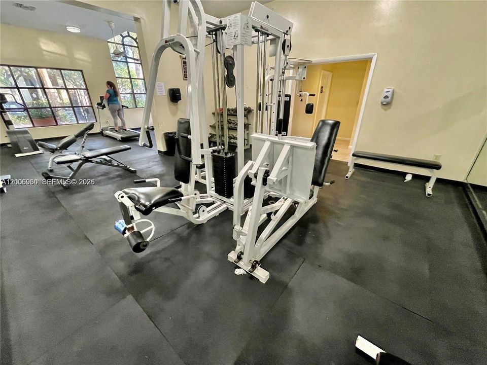 Fitness area featuring rubber flooring, large multi-pane windows, and high ceilings