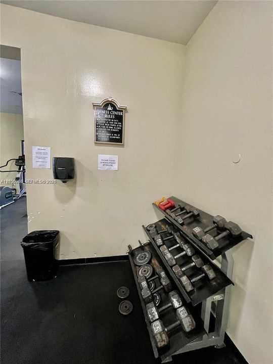 Fitness center featuring rubberized flooring and a multi-tiered metal weight rack with various hand weights