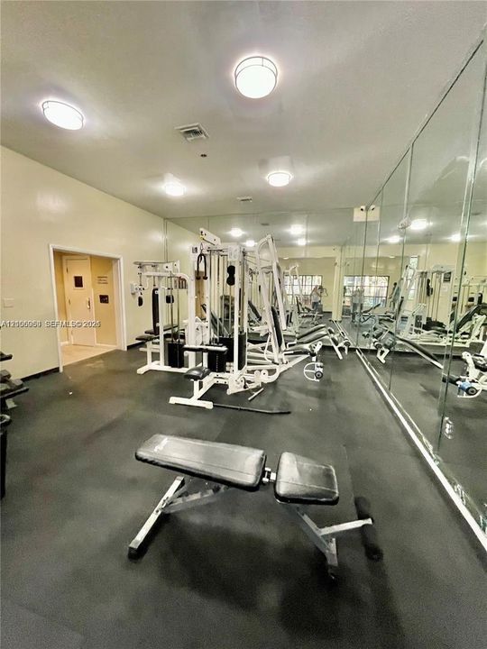 Fitness facility featuring full-wall mirrors, durable rubberized flooring, and recessed ceiling lighting