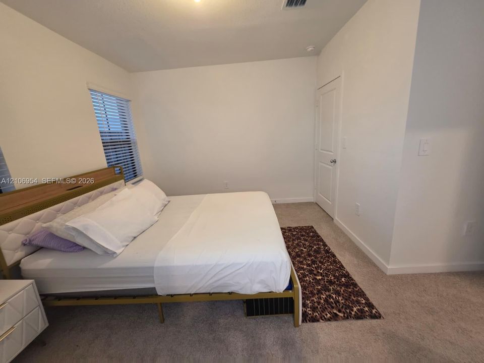 Neutral-toned carpeted flooring, two-panel interior door, and window with horizontal blinds
