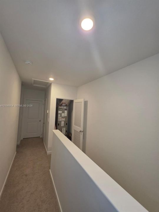 Hallway featuring neutral carpet flooring, recessed ceiling lighting, and louvered door access to utility mechanicals