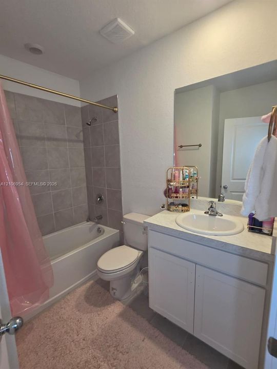 Bathroom featuring a vanity with an integrated basin, neutral countertop, wall-mounted mirror, and a tub-shower combination with full-height tile surround