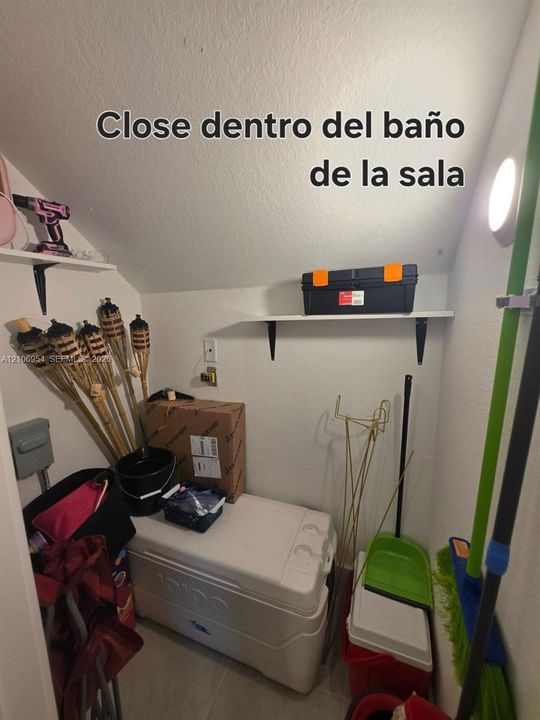 Storage closet featuring two wall-mounted shelving units and an integrated electrical outlet
