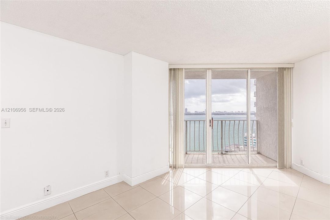 Large-format tile flooring, expansive sliding glass doors, and a private balcony featuring a metal railing