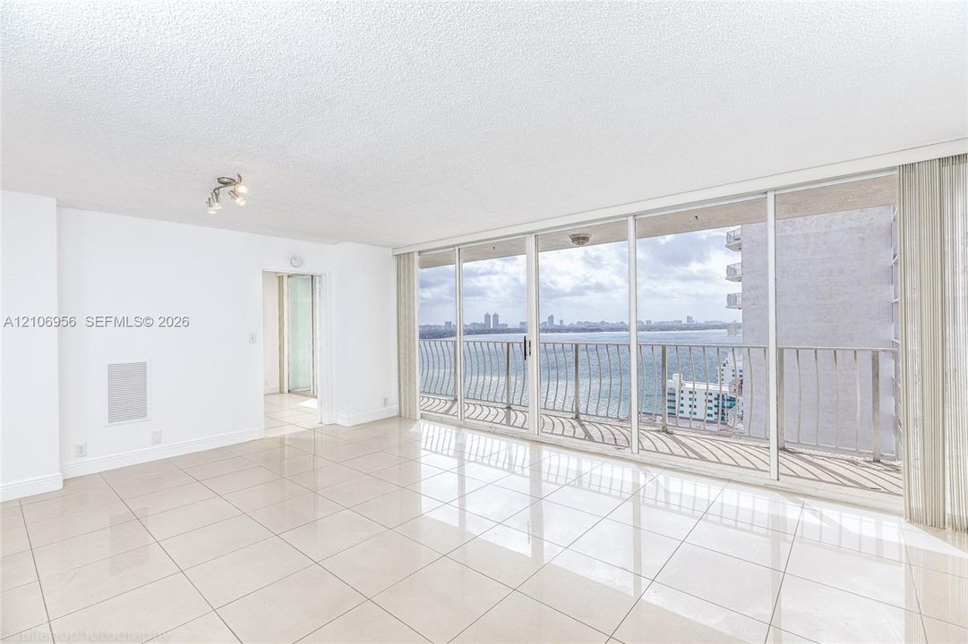 Open-concept space featuring polished tile flooring, floor-to-ceiling glass sliding doors, and a private balcony with metal railing