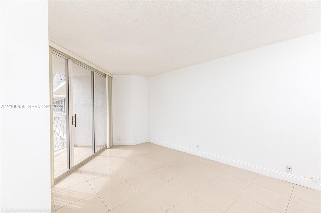 Large-format tile flooring, oversized sliding glass doors, and an attached balcony with decorative metal railing