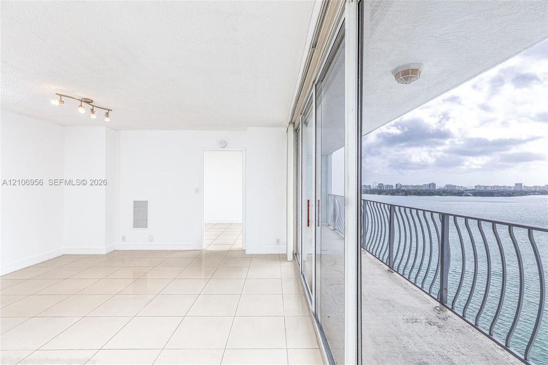 Interior space featuring oversized floor tiles, sliding glass balcony doors, a multi-bulb track lighting fixture, and a metal balcony railing