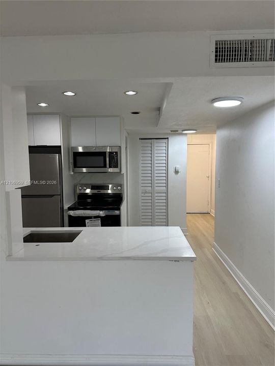 Kitchen featuring white cabinetry, stone-finish countertops, stainless steel appliances, recessed lighting, and wood-finish flooring