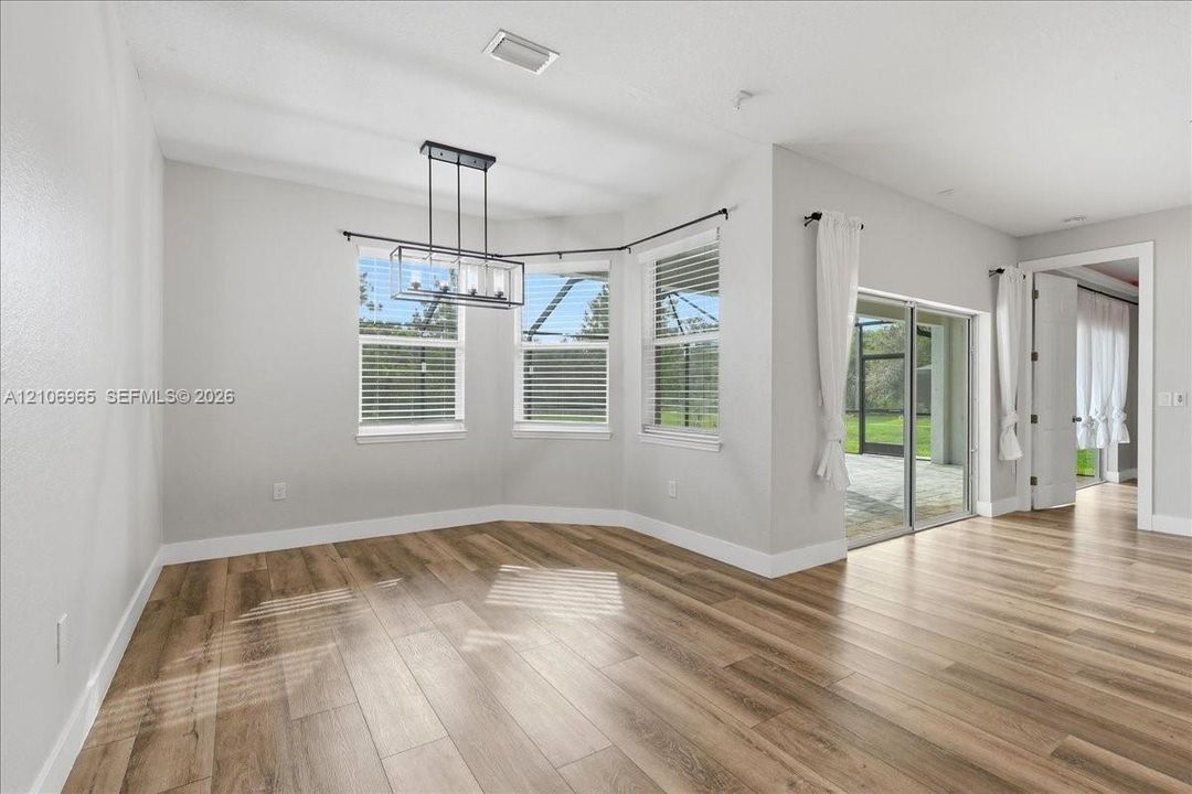 Dining area featuring wood-finish flooring, a multi-light metal chandelier, a bay window configuration, and sliding glass doors