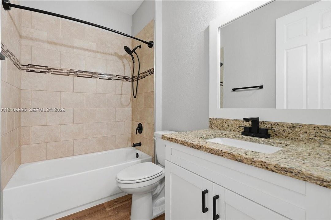 White vanity featuring a stone-look countertop, rectangular undermount sink, and matte black faucet