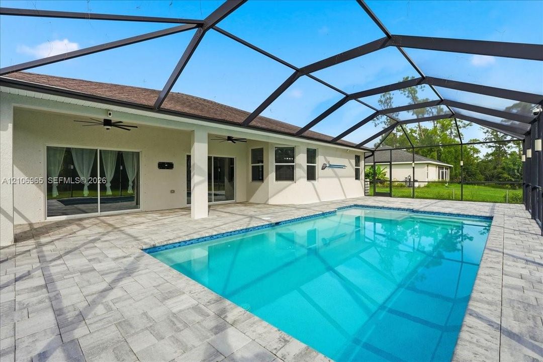 Screen-enclosed patio featuring a paver deck, built-in ceiling fans, recessed exterior lighting, and an inground swimming pool with tiled coping