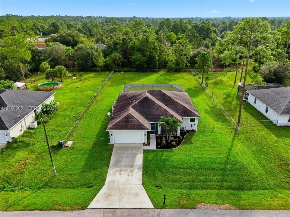 Single-story residence featuring a concrete driveway, two-car garage, screened rear lanai, and fenced backyard lot