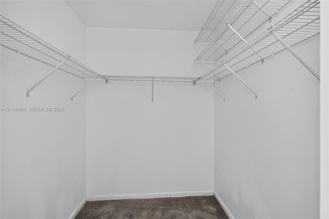 Walk-in storage area featuring white wire shelving and neutral carpeting