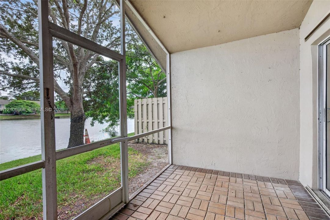 Screened-in patio with brick-patterned flooring, textured wall finish, and a water-side setting
