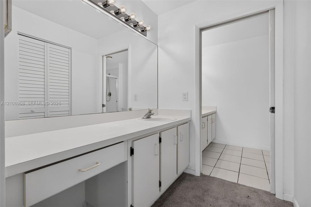 Bathroom vanity featuring a solid surface countertop, integrated sink, full-width wall mirror, and five-bulb vanity light fixture