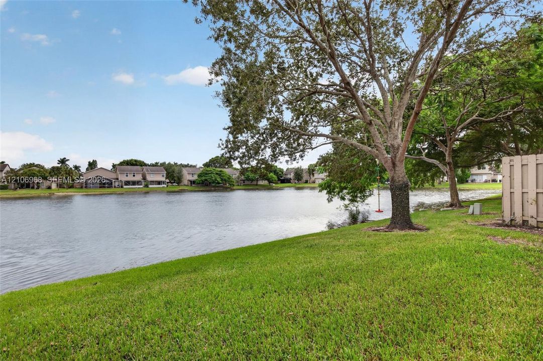 Waterfront lot featuring a manicured lawn, mature trees, and a solid privacy fence