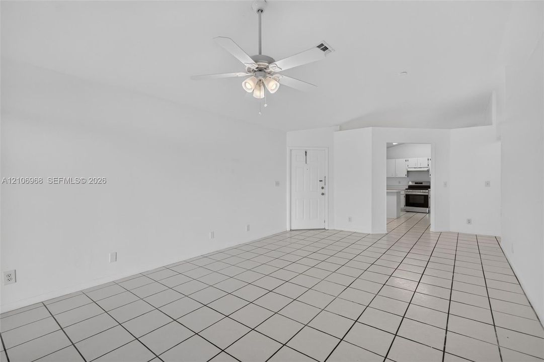 Interior space featuring neutral tile flooring, vaulted ceilings, and a ceiling fan with integrated lighting