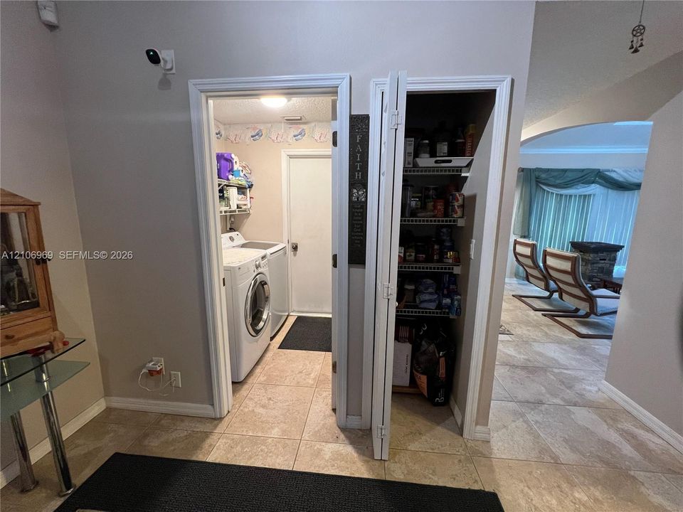 Utility room featuring tile flooring and laundry hookups, paired with a dedicated pantry featuring wire shelving