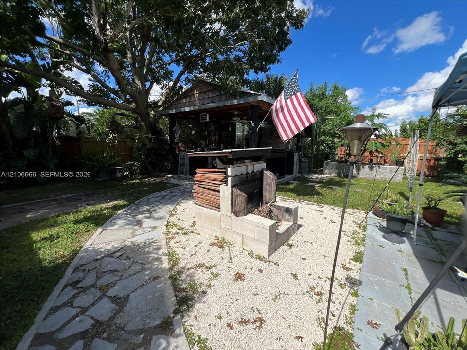 Backyard featuring a covered wood-framed gazebo, masonry fire pit, stone-paver walkway, and gravel ground cover